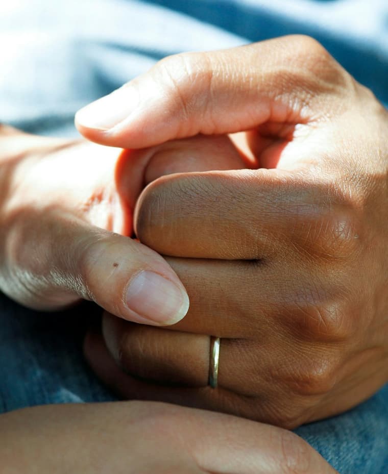 Duas mãos se segurando, uma delas com aliança